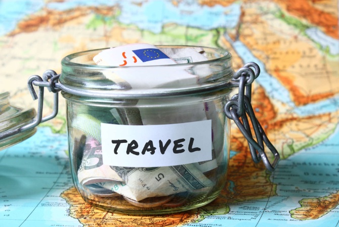 a glass jar with a travel label filled with dollars on a map